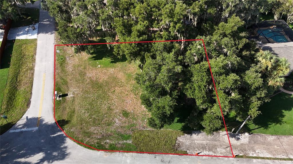 An aerial view shows a vacant, wooded residential lot outlined in red along a street — LAKESIDE DRIVE, YALAHA, FL