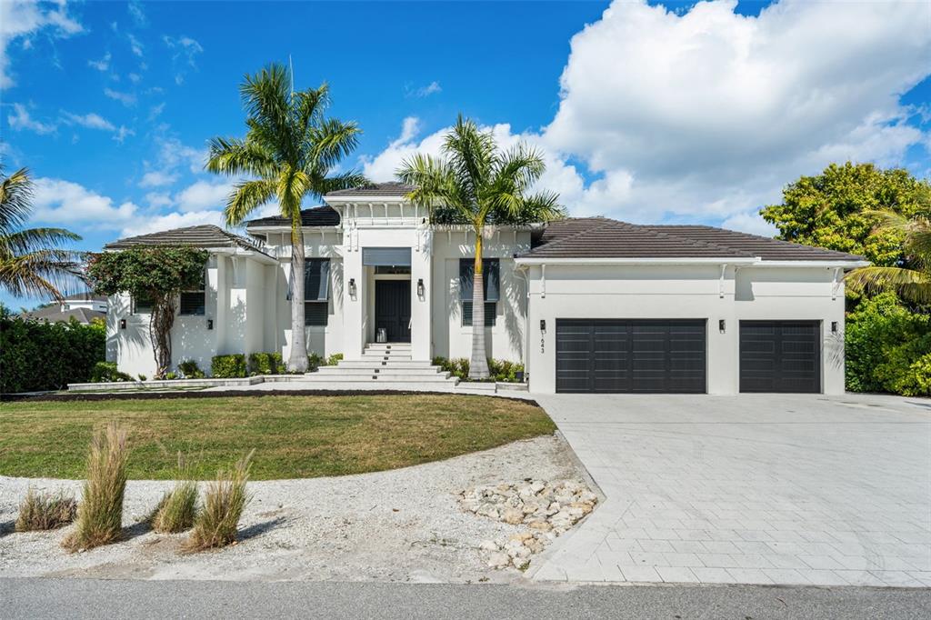 A white single-story house features a dark-tiled roof, a paved driveway, and two palm trees — 1643 STANFORD LANE, SARASOTA, FL