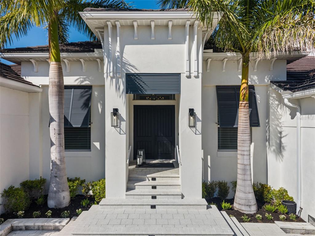 A waterfront house with a pool, palm trees, and a boat docked in the foreground — 1643 STANFORD LANE, SARASOTA, FL