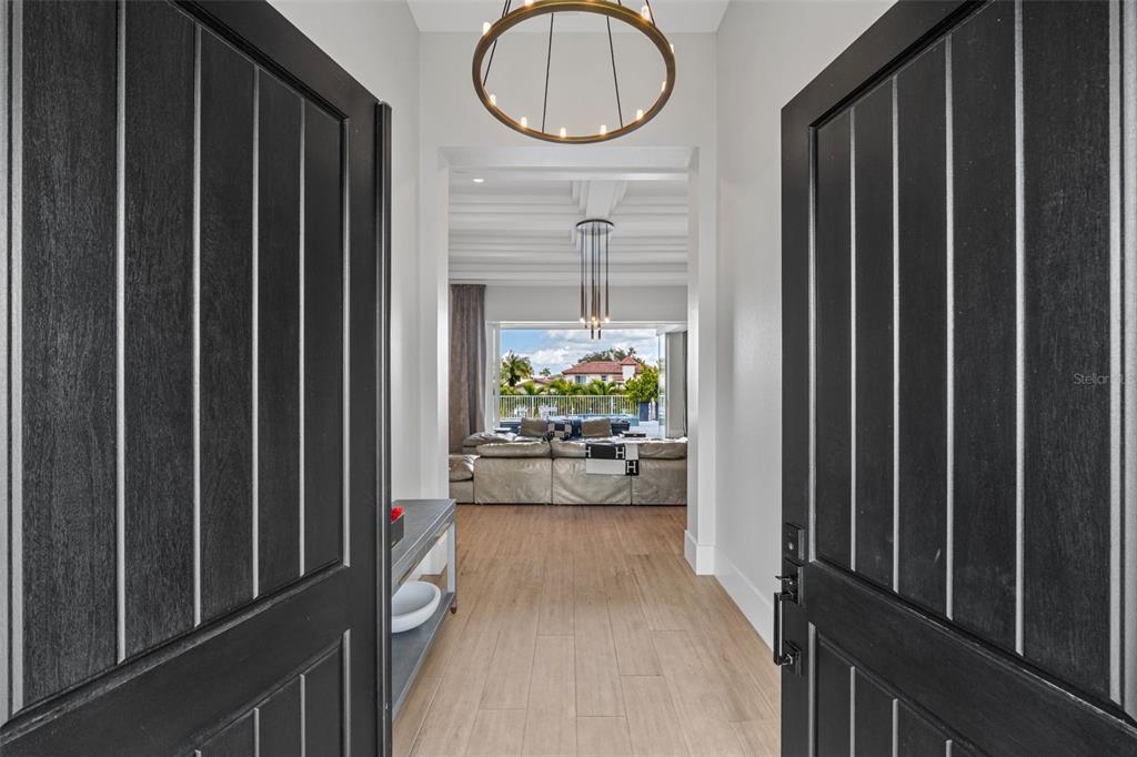 The front entrance of a white house features a dark double door, shutters, and palm trees — 1643 STANFORD LANE, SARASOTA, FL