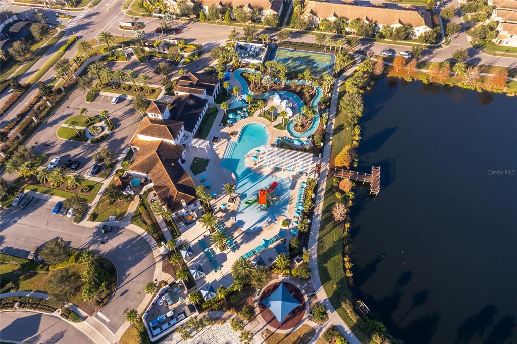 An aerial view shows a community clubhouse with a swimming pool, lazy river, and lake — 1690 LIMA AVENUE, KISSIMMEE, FL