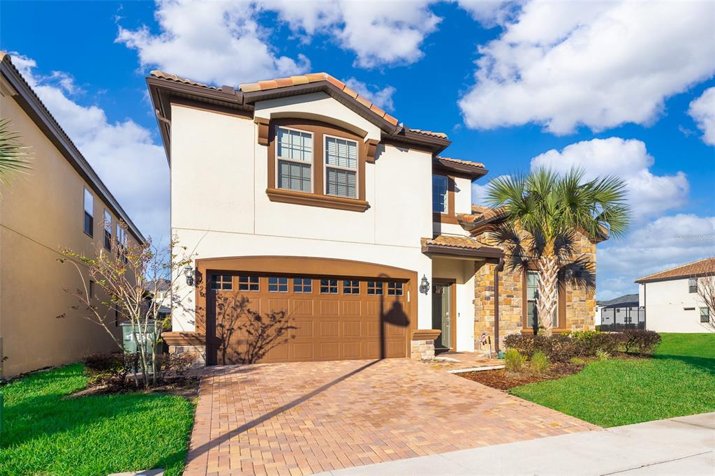 A two-story house with a brick paver driveway, a two-car garage, and stone facade accents — 1690 LIMA AVENUE, KISSIMMEE, FL