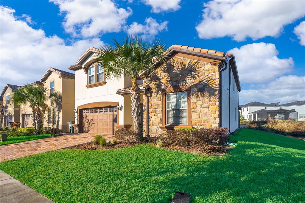 A two-story house with a stone facade, a paved driveway, and a palm tree — 1690 LIMA AVENUE, KISSIMMEE, FL