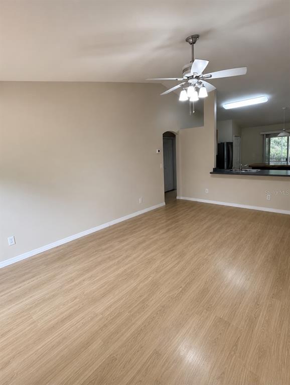 A living room with light wood-look flooring, a vaulted ceiling, and a ceiling fan — 2743 SOMERSET, PALM BAY, FL