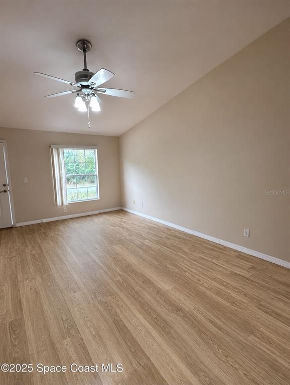 An empty room features light wood-look flooring, beige walls, a ceiling fan, and a window — 2743 SOMERSET, PALM BAY, FL