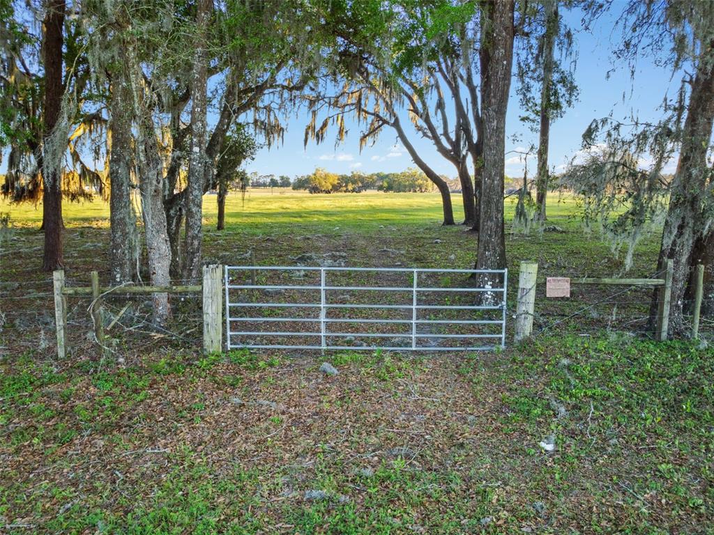 A metal gate stands between two wooden posts at the entrance to a grassy field — 0 W CR 476, BUSHNELL, FL