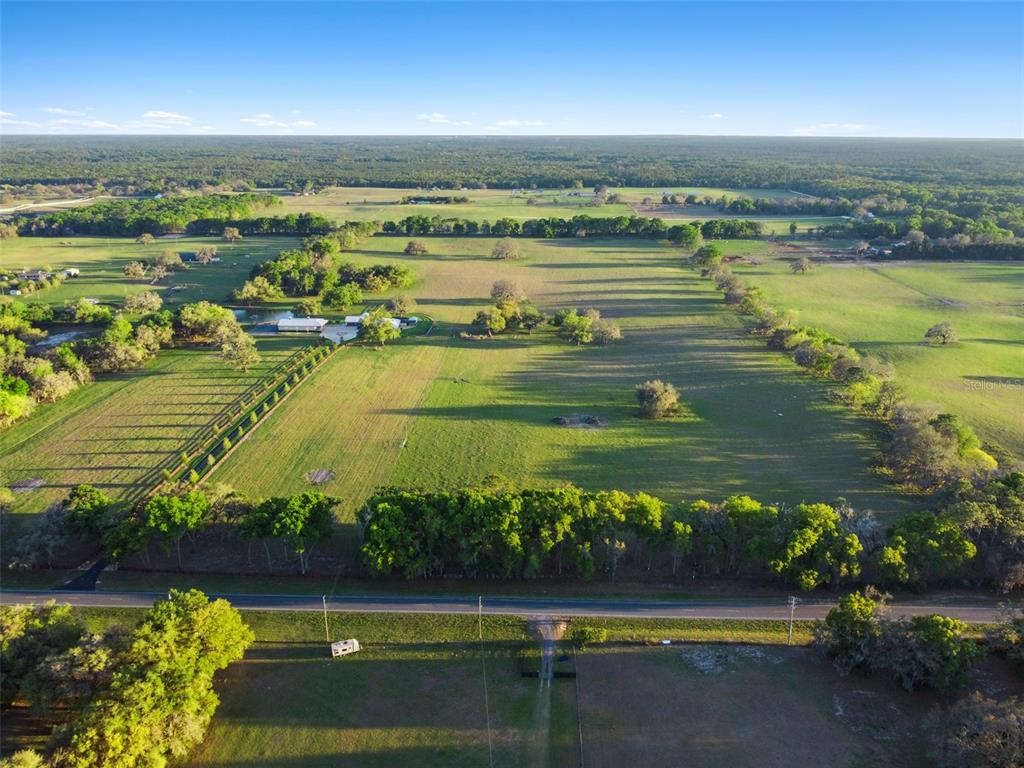 An aerial view shows a large, grassy rural property with a house, pond, and trees — 0 W CR 476, BUSHNELL, FL