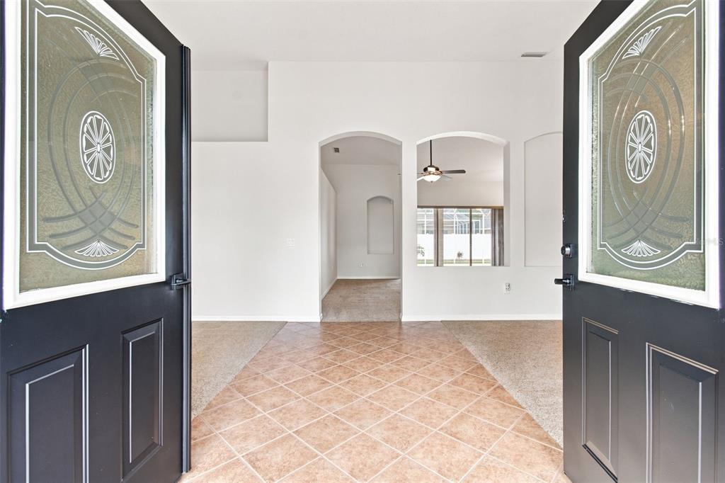 The view from an entryway shows a tiled foyer leading to carpeted rooms and arched doorways — 10260 SHADOW BRANCH DRIVE, TAMPA, FL
