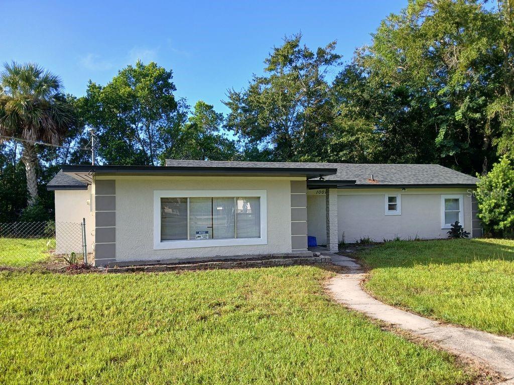 A single-story house with a light-colored exterior, a large front window, and a concrete walkway — 1001 SANTA BARBARA DRIVE, SANFORD, FL