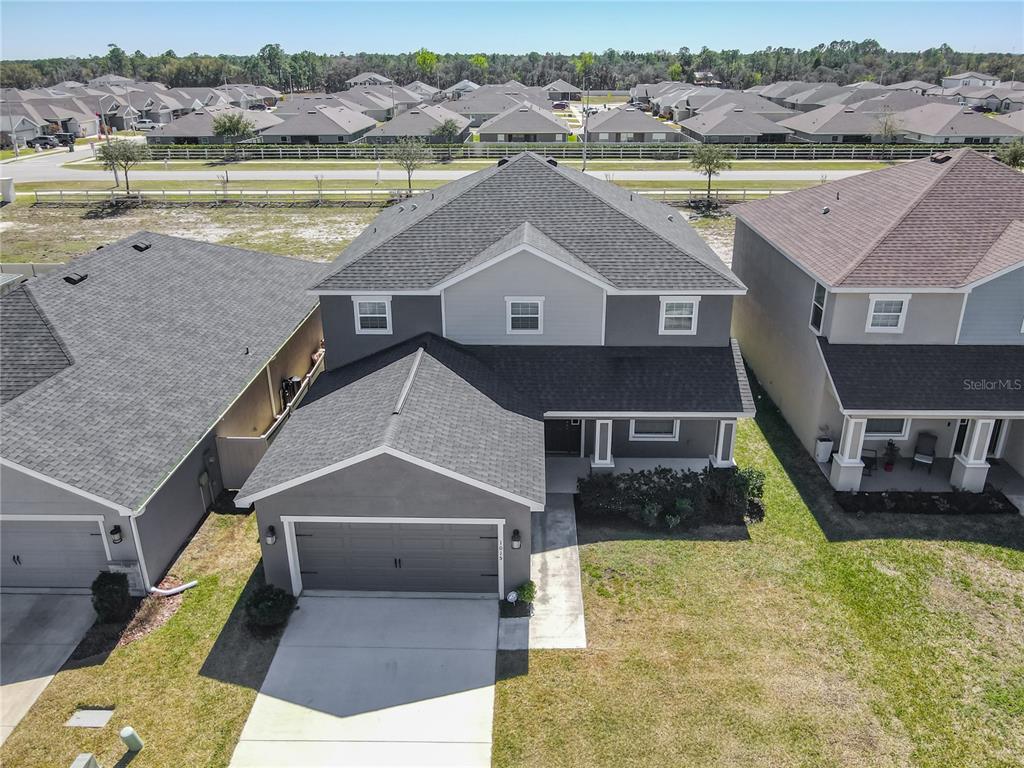 An aerial view shows a two-story gray house with a garage and a shingled roof — 1015 CORSO DRIVE, WINTER HAVEN, FL