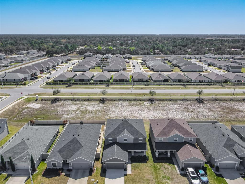An aerial view shows a suburban neighborhood with rows of houses and a vacant lot — 1015 CORSO DRIVE, WINTER HAVEN, FL