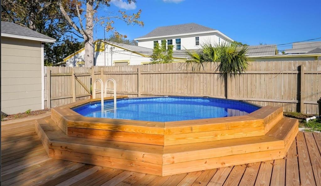 An above-ground octagonal swimming pool with a wooden deck and surrounding privacy fence — 5340 5TH AVENUE S, ST PETERSBURG, FL