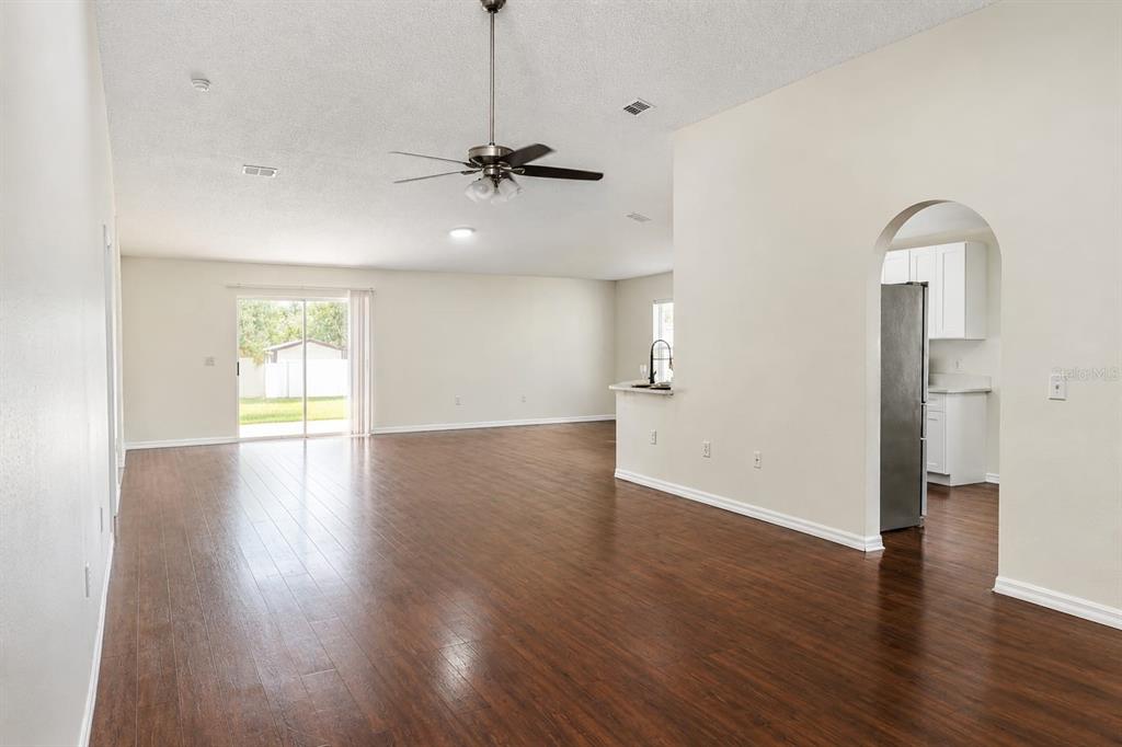 An open-concept living area features dark wood flooring, a ceiling fan, and an arched kitchen entrance — 13402 COPPER HEAD DRIVE, RIVERVIEW, FL