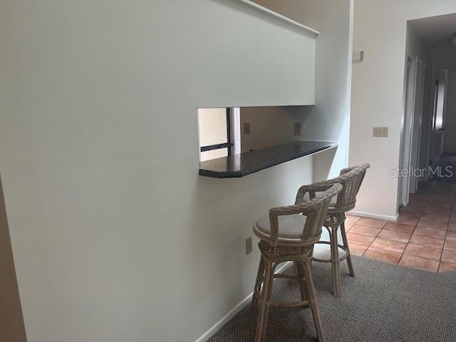 A kitchen pass-through window with a granite counter and two wicker bar stools — 9410 NAKOMA WAY UNIT H, WEEKI WACHEE, FL