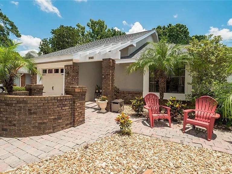 A single-story house features a brick facade, a paver walkway, and two red Adirondack chairs — 3161 BERRIDGE LANE, ORLANDO, FL