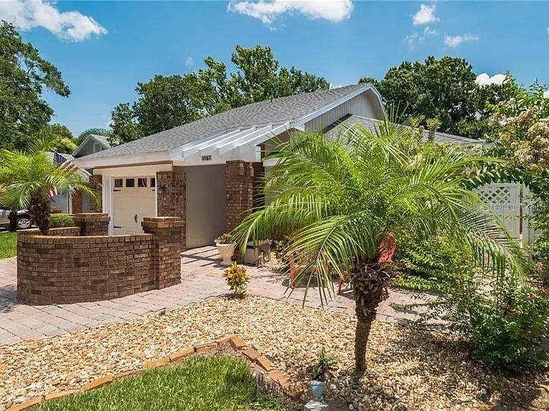 A brick-walled courtyard leads to the entrance of a house with a palm tree — 3161 BERRIDGE LANE, ORLANDO, FL