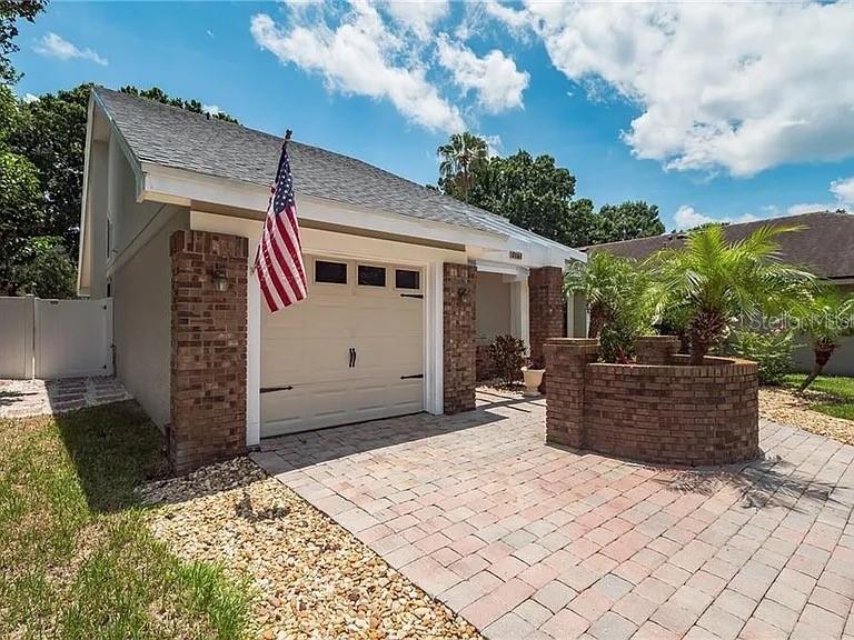 A brick-accented house features a garage with an American flag and a paved driveway — 3161 BERRIDGE LANE, ORLANDO, FL