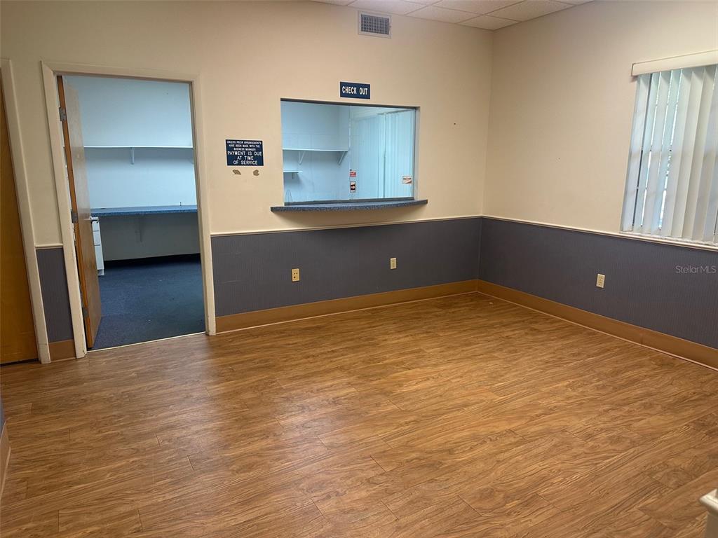 An office reception area features wood-look flooring, a checkout window, and a separate side room — 4611 NW 53RD AVENUE, GAINESVILLE, FL
