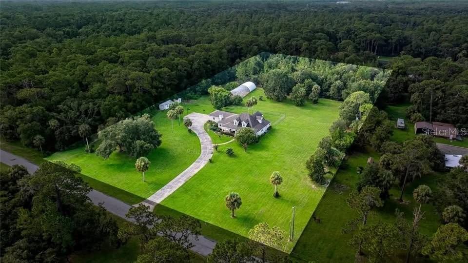 An aerial view shows a house with a long driveway on a large, grassy lot — 10264 W SPRINGTREE LANE, CRYSTAL RIVER, FL