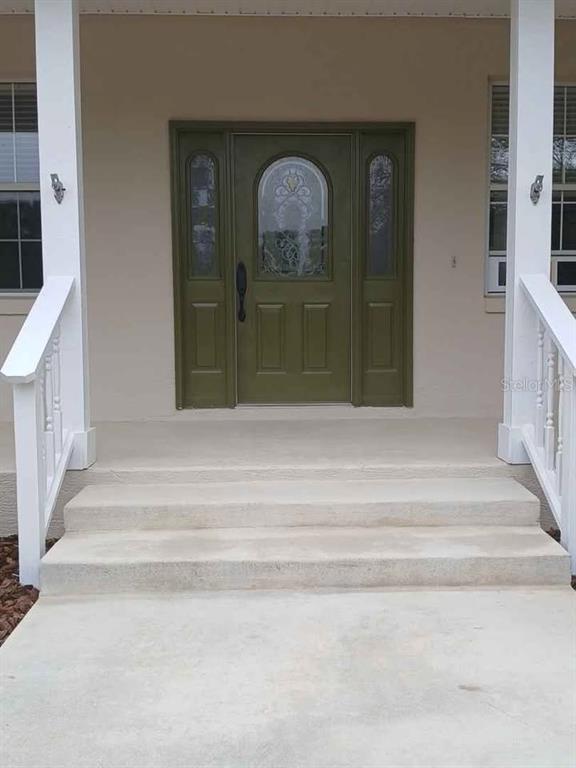 A front porch with concrete steps leads to a green door with glass sidelights — 10264 W SPRINGTREE LANE, CRYSTAL RIVER, FL