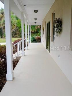 A long, covered outdoor porch with white columns, light flooring, and recessed ceiling lights — 10264 W SPRINGTREE LANE, CRYSTAL RIVER, FL