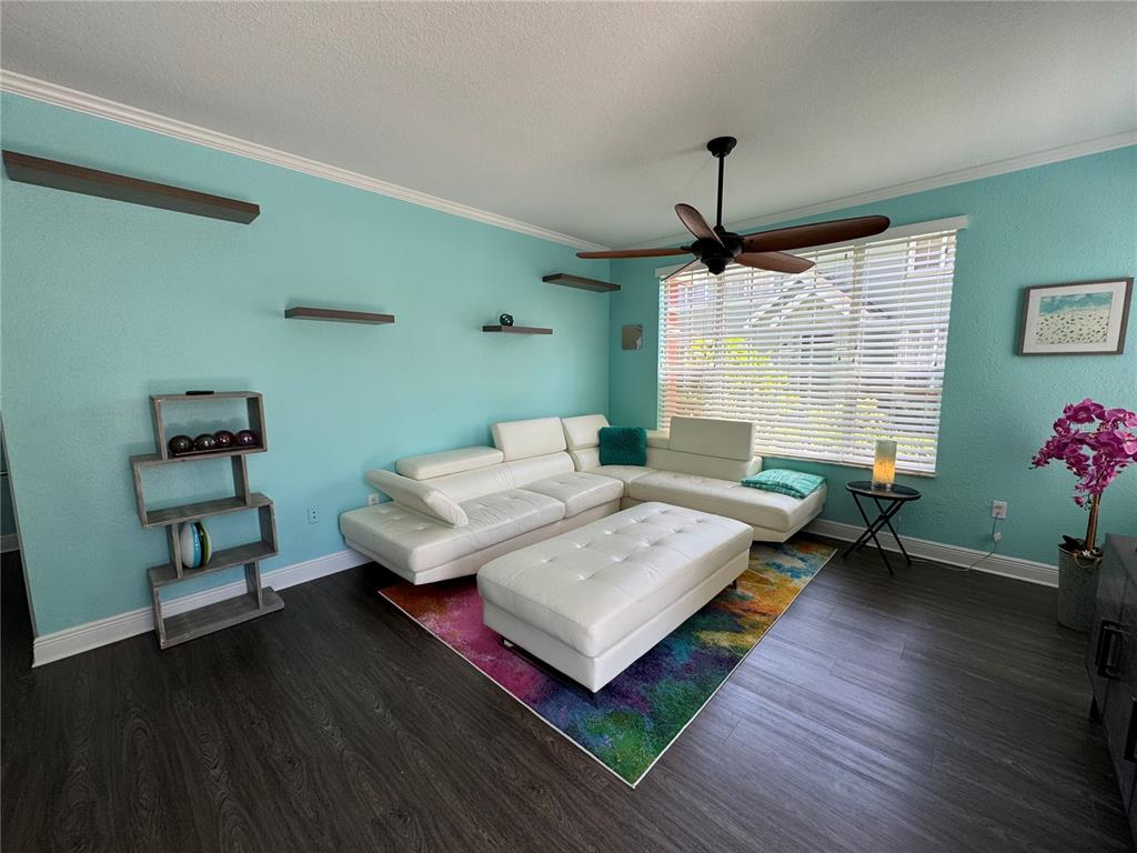 A living room features a white sectional sofa, a colorful rug, and floating wall shelves — 9288 LAKE CHASE ISLAND WAY, TAMPA, FL