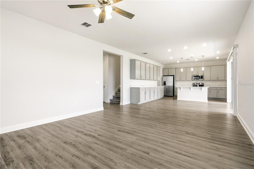 An open-concept kitchen and living area features light gray cabinetry, stainless appliances, and wood-look flooring — 1128 SUGARWOOD STREET, DAVENPORT, FL