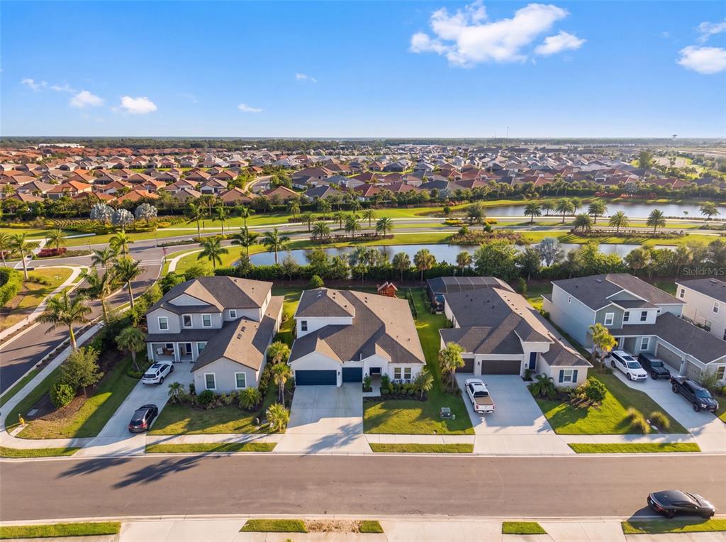 An aerial view shows several suburban houses with driveways and a nearby pond and neighborhood — 16552 STAR GRASS CIRCLE, BRADENTON, FL