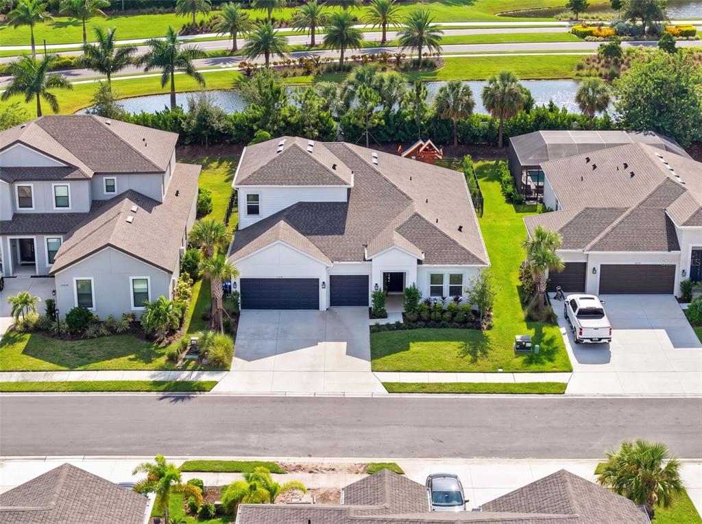 An aerial view shows a suburban house with a gray roof and a three-car garage — 16552 STAR GRASS CIRCLE, BRADENTON, FL
