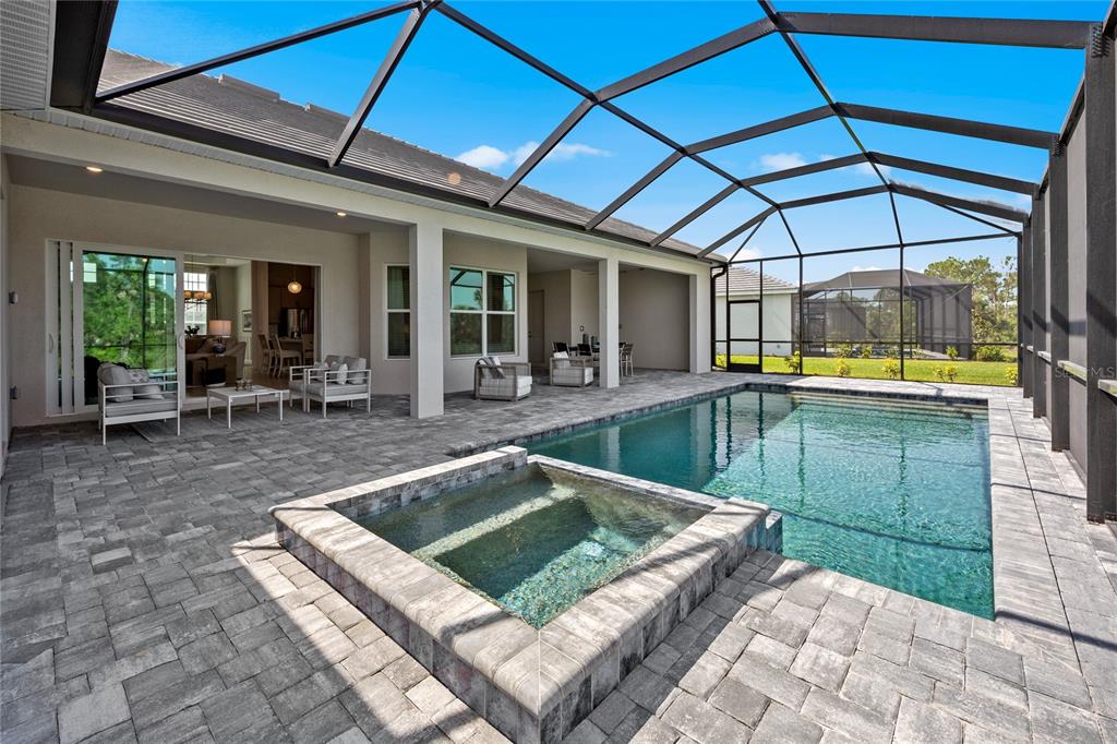 A covered patio features a swimming pool, a raised spa, and stone paver flooring — 20013 TROUT TERRACE, LAKEWOOD RANCH, FL
