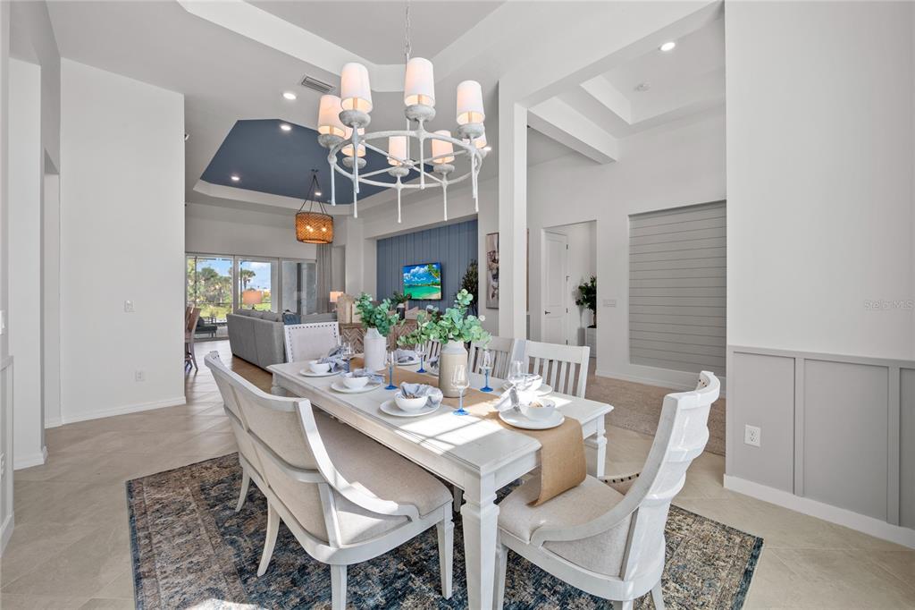 A dining room features a white table, upholstered chairs, a chandelier, and a blue ceiling — 20013 TROUT TERRACE, LAKEWOOD RANCH, FL