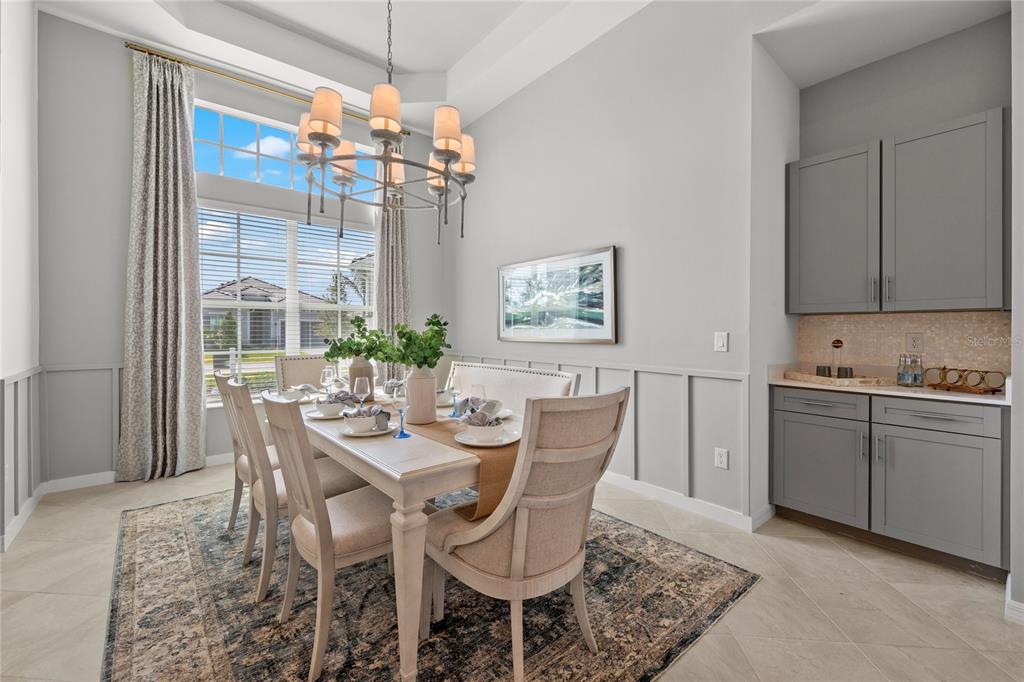 A dining room features a chandelier, a table with six chairs, and gray built-in cabinetry — 20013 TROUT TERRACE, LAKEWOOD RANCH, FL
