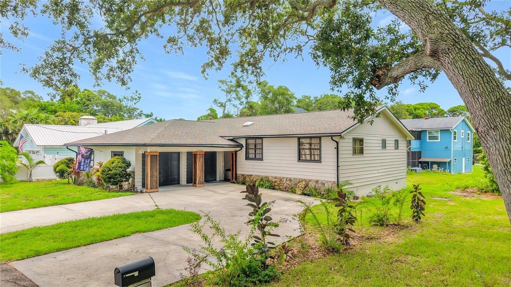 A single-story house with light siding, a stone base, and a two-car garage — 12756 POINSETTIA AVENUE, SEMINOLE, FL