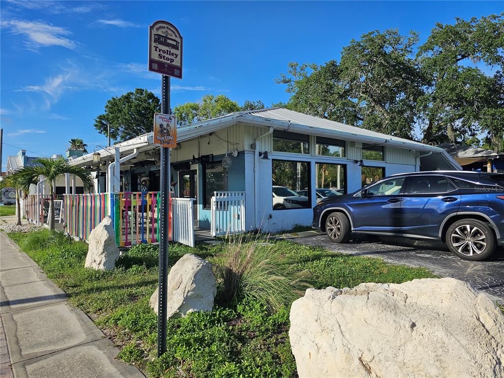 A blue building with a trolley stop sign and a parked car in the foreground — 606 N PINELLAS AVENUE, TARPON SPRINGS, FL