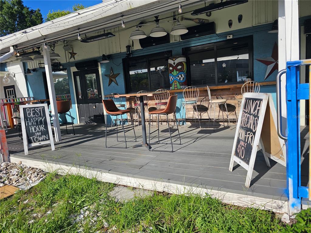 An outdoor patio area features a wooden deck, bar-style seating, and signage for a restaurant — 606 N PINELLAS AVENUE, TARPON SPRINGS, FL