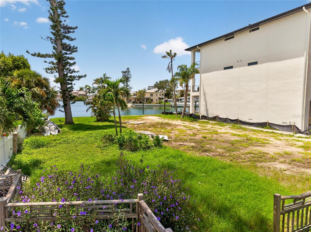 A grassy lot sits next to a multi-story building overlooking a canal with palm trees — 331 BOCA CIEGA DRIVE, MADEIRA BEACH, FL