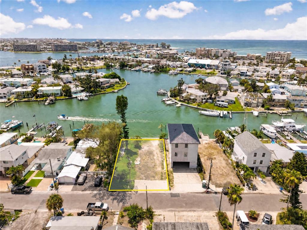 An aerial view shows a vacant waterfront lot highlighted in yellow between two houses — 331 BOCA CIEGA DRIVE, MADEIRA BEACH, FL