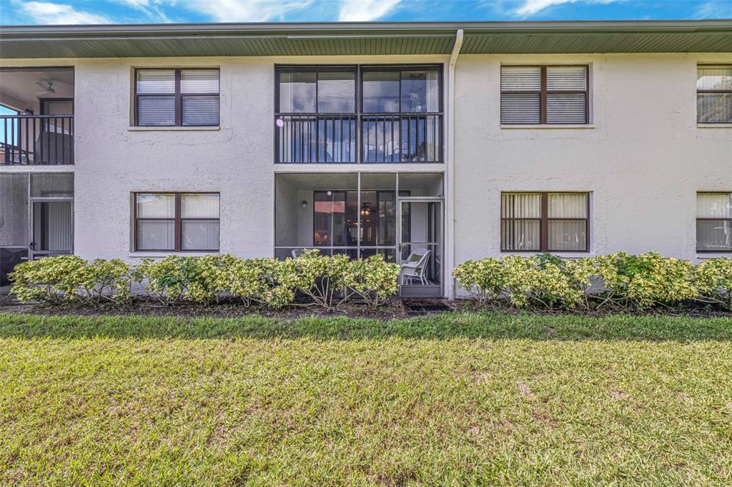 A two-story apartment building exterior features a screened-in ground floor patio and upper balcony — 4520 47TH AVENUE W UNIT 103, BRADENTON, FL