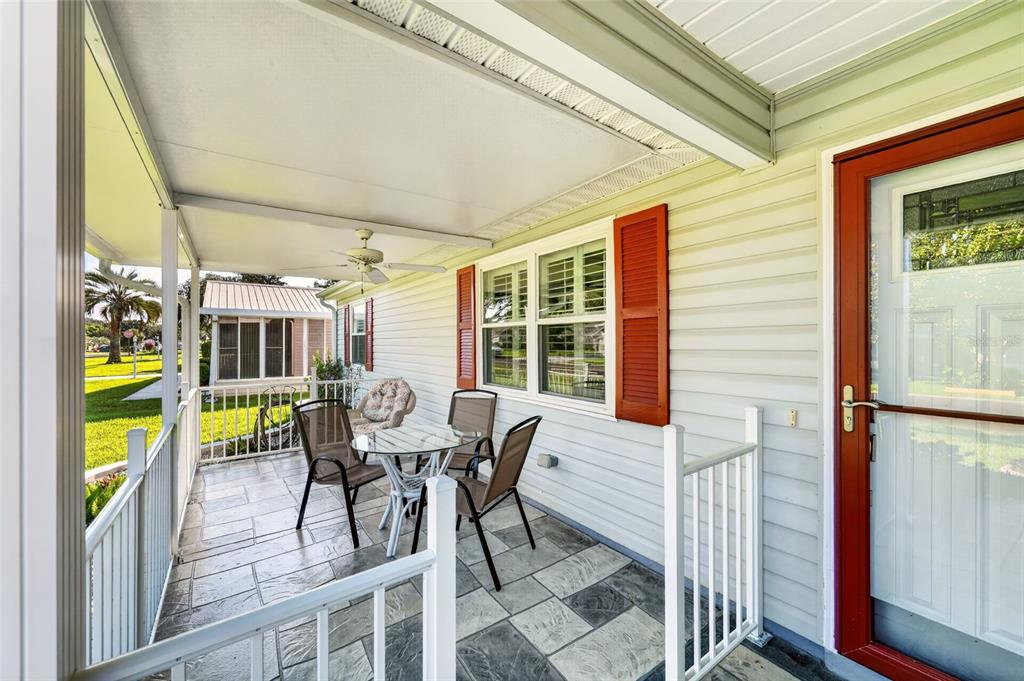 A covered porch with tiled flooring, patio furniture, and a ceiling fan beside a house — 1218 SANTOS PLACE, THE VILLAGES, FL