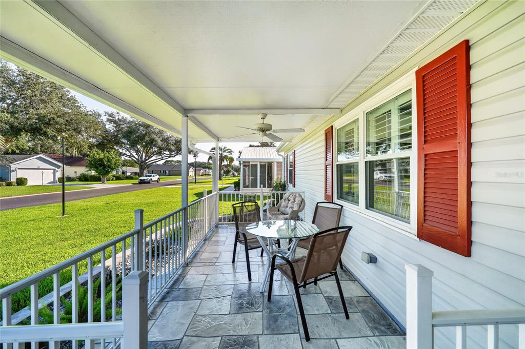 A covered porch features a tiled floor, a ceiling fan, and a small dining set — 1218 SANTOS PLACE, THE VILLAGES, FL
