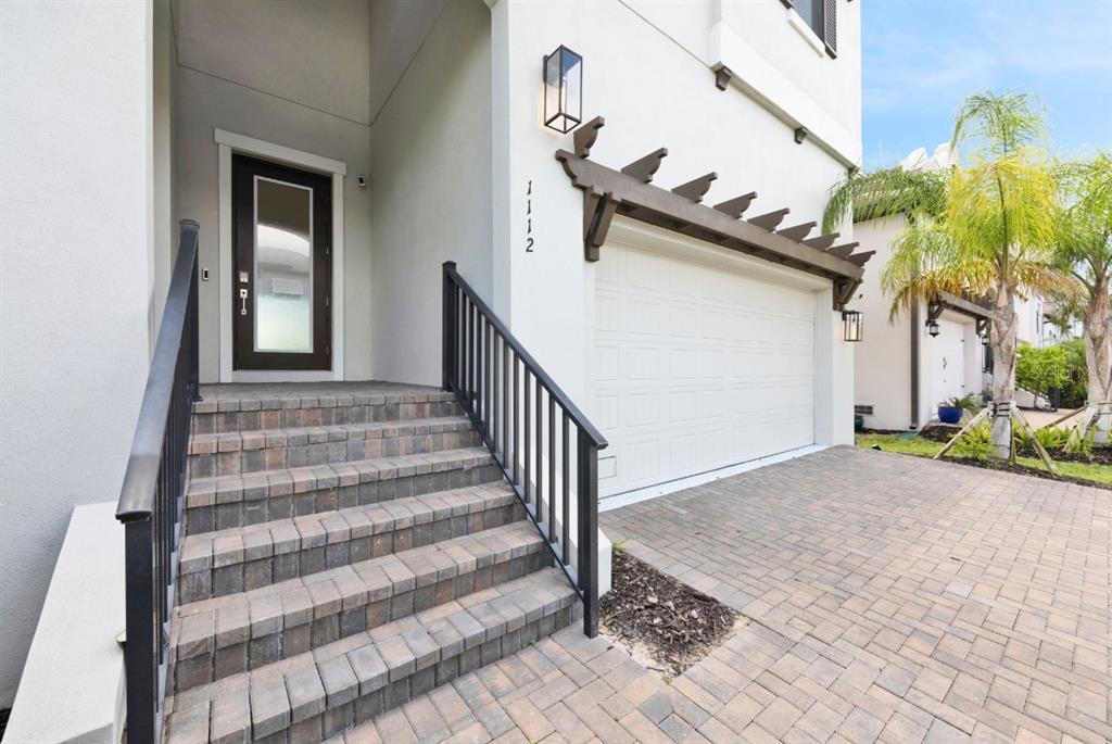 A paved driveway leads to a white house with a garage and front entry stairs — 1112 SEAGRAPE DRIVE, RUSKIN, FL