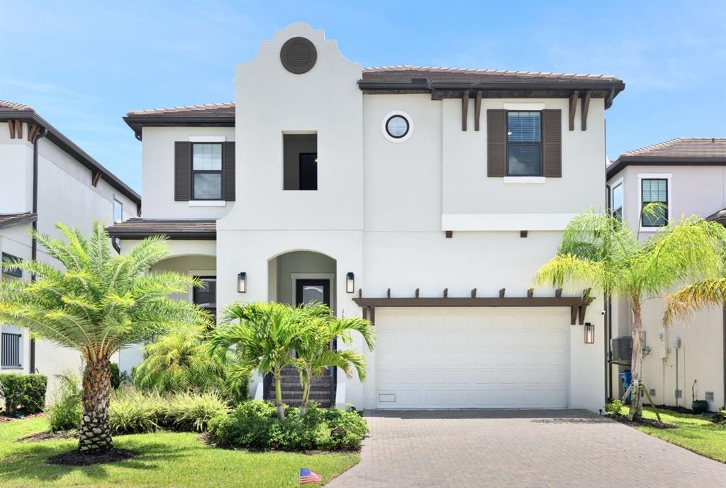 A two-story stucco house features a tiled roof, a garage, and palm trees — 1112 SEAGRAPE DRIVE, RUSKIN, FL