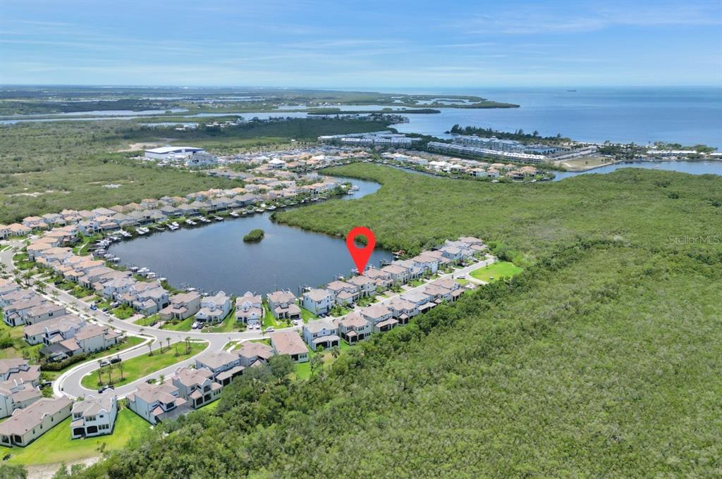An aerial view shows a residential community with houses situated along a lake and mangroves — 1112 SEAGRAPE DRIVE, RUSKIN, FL