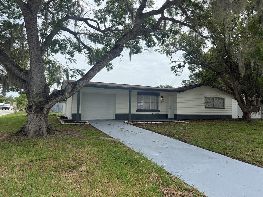 A single-story house with a stone facade, white chimney, and a covered front porch — 3019 LLOYD DRIVE, HOLIDAY, FL