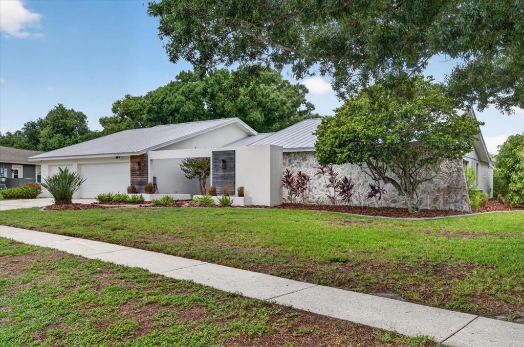 A single-story house with a white metal roof, stone facade, and a modern entryway — 2862 SHADY OAK COURT, CLEARWATER, FL