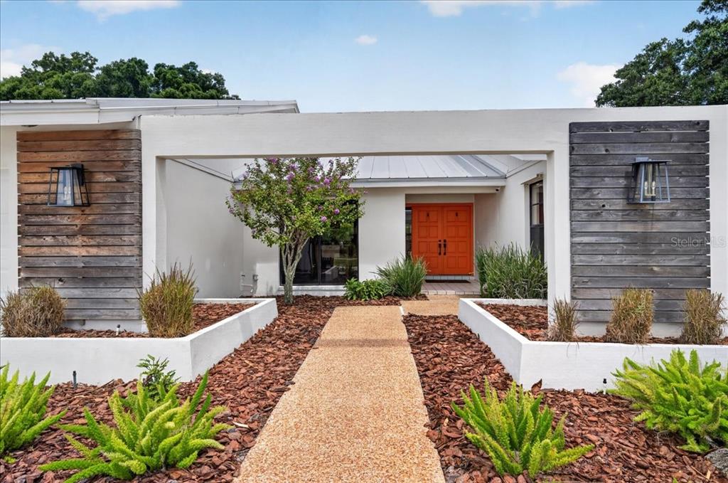 The exterior of a modern house features a bright orange door and wood-paneled accents — 2862 SHADY OAK COURT, CLEARWATER, FL