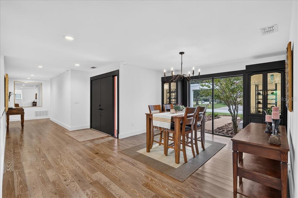 A dining area with wood floors, a dark chandelier, and a sliding glass door — 2862 SHADY OAK COURT, CLEARWATER, FL