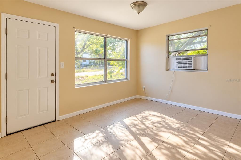 An interior room features light-colored walls, tiled flooring, a white door, and a window air conditioner — 157 E NORTHSIDE DRIVE UNIT 1, LAKE WALES, FL