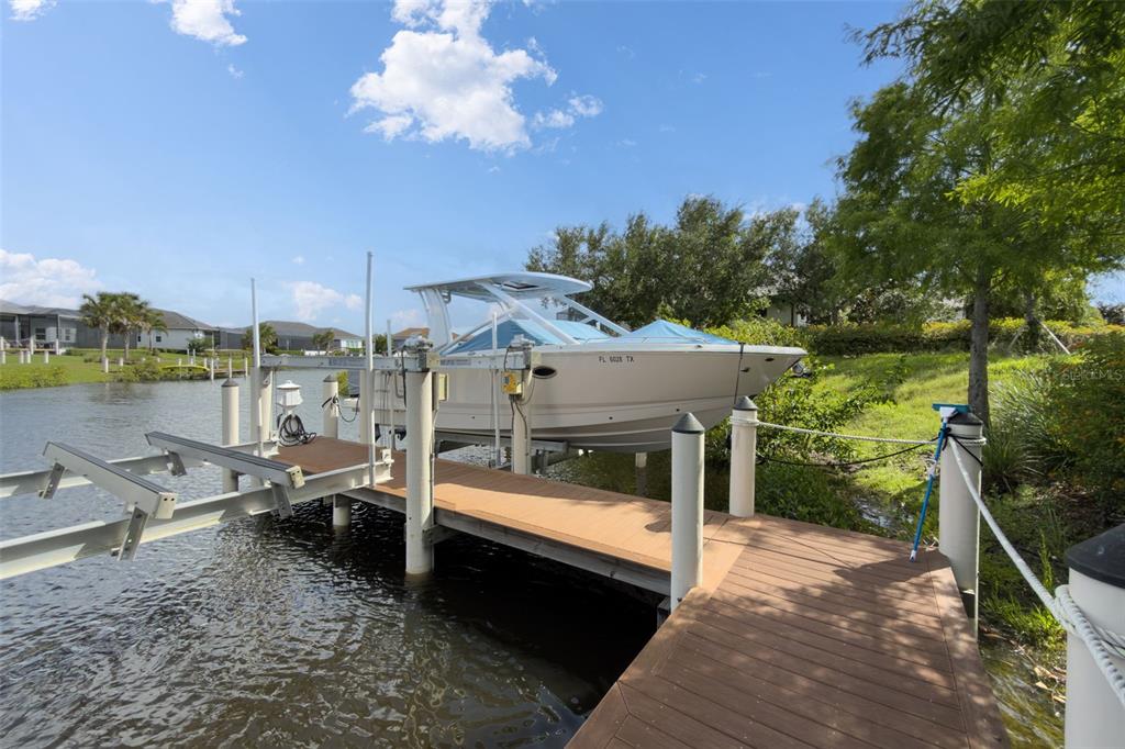 A boat sits on a lift attached to a wooden dock along a canal — 11721 RIVE ISLE RUN, PARRISH, FL