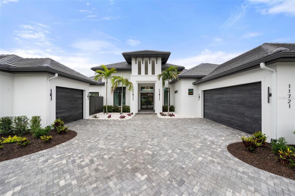 A modern white house with a gray tile roof and two dark wood garage doors — 11721 RIVE ISLE RUN, PARRISH, FL